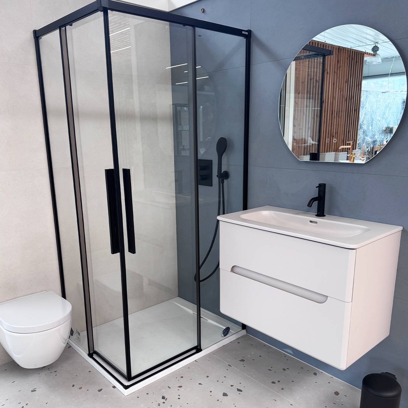 Baño con mampara negra y revestimiento azul